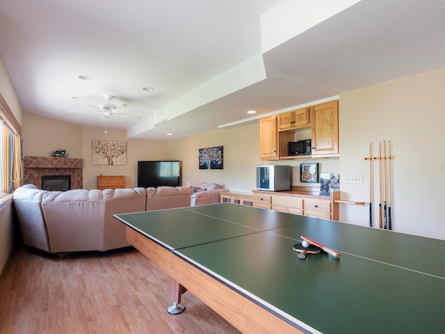 recreation room featuring ceiling fan, light wood-style flooring, a tile fireplace, and recessed lighting