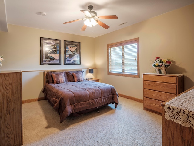 bedroom featuring light colored carpet, baseboards, and ceiling fan