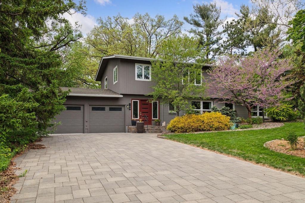 154 Woodland Dr, Burnsville, MN 55337 - view of front of house with decorative driveway, an attached garage, and a front lawn
