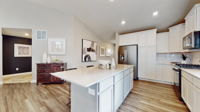 kitchen featuring stainless steel appliances, light wood-type flooring, vaulted ceiling, light countertops, and white cabinets