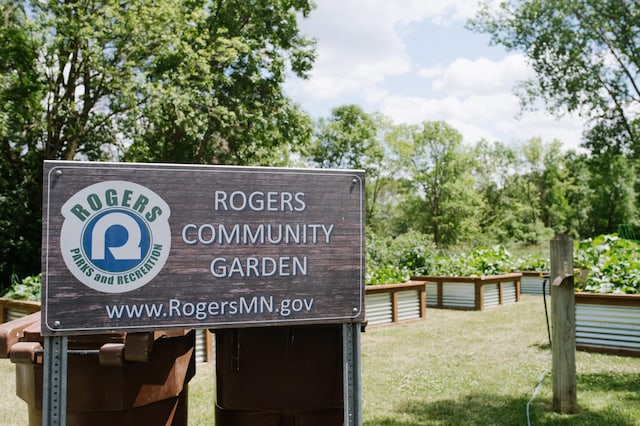 community / neighborhood sign featuring a yard and view of scattered trees