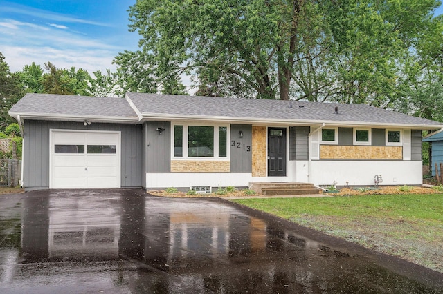 3213 63rd Ave N, Brooklyn Center, MN 55429 - single story home with asphalt driveway, a garage, stone siding, a front yard, and a shingled roof