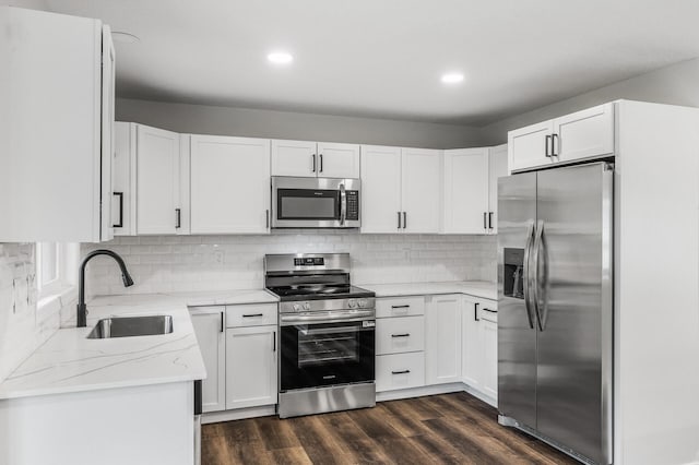 3213 63rd Ave N, Brooklyn Center, MN 55429 - kitchen with stainless steel appliances, a sink, light stone counters, dark wood-style flooring, and white cabinets