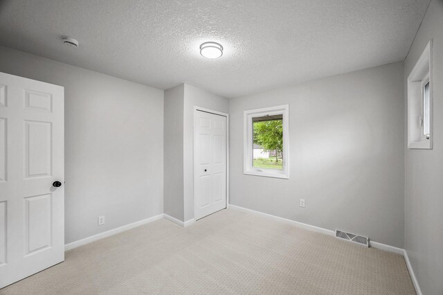 3213 63rd Ave N, Brooklyn Center, MN 55429 - unfurnished bedroom with a textured ceiling, light carpet, baseboards, and a closet