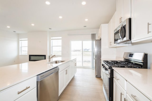 kitchen featuring stainless steel appliances, white cabinetry, a sink, light countertops, and recessed lighting