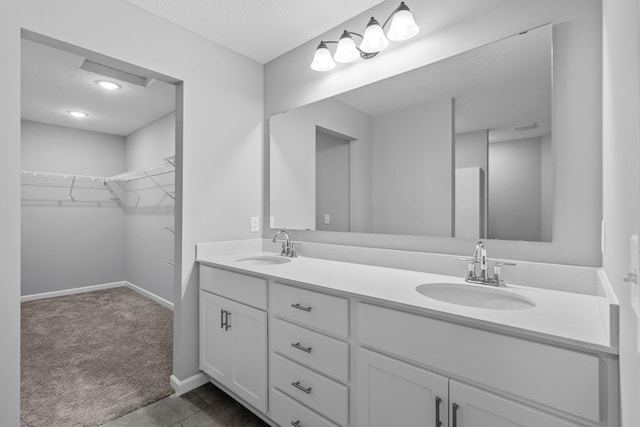14617 Quintana St NW, Ramsey, MN 55303 - bathroom with a textured ceiling, double vanity, a walk in closet, and baseboards