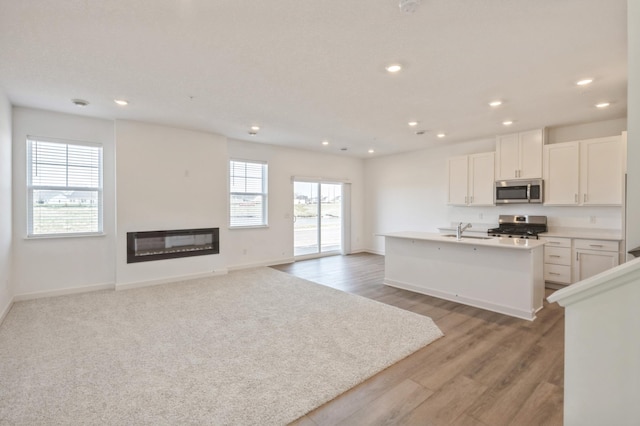 kitchen featuring appliances with stainless steel finishes, a sink, recessed lighting, a kitchen island with sink, and open floor plan