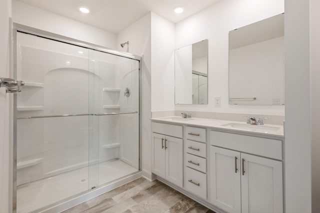bathroom featuring a stall shower, double vanity, and recessed lighting