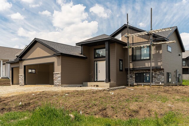 1806 Brandt Dr NE, Byron, MN 55920 - view of front facade featuring stone siding, a garage, driveway, a shingled roof, and board and batten siding