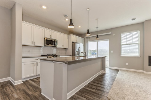 kitchen with stainless steel appliances, baseboards, an island with sink, dark wood-type flooring, and recessed lighting