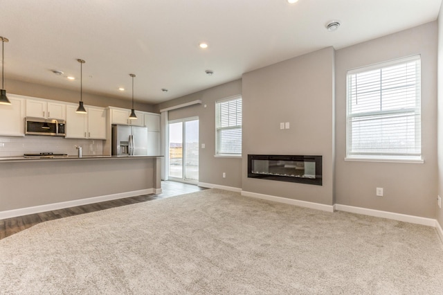 kitchen with appliances with stainless steel finishes, white cabinets, tasteful backsplash, pendant lighting, and recessed lighting