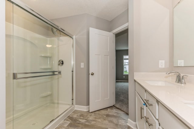 bathroom featuring a shower stall, baseboards, and double vanity