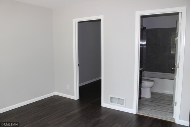1310 Pacific St, Saint Paul, MN 55106 - unfurnished bedroom featuring wood finished floors, a walk in closet, baseboards, a closet, and ensuite bathroom