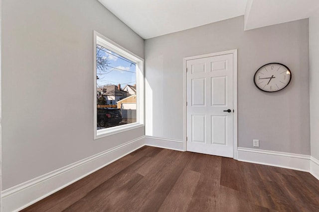 empty room with dark wood-style flooring and baseboards
