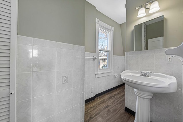 bathroom with tile walls, wood finished floors, and a wainscoted wall