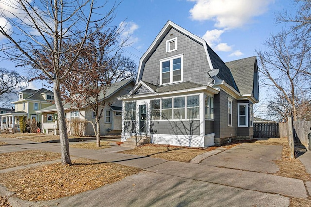 colonial inspired home with roof with shingles, a gambrel roof, and fence