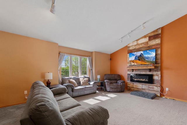 carpeted living area with rail lighting, a fireplace, and vaulted ceiling