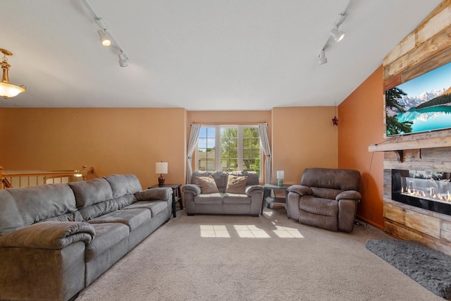 carpeted living area featuring rail lighting and a stone fireplace