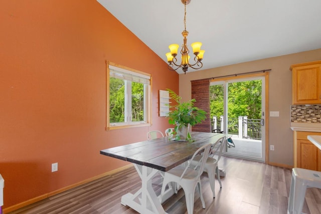 dining space with a chandelier, light wood finished floors, lofted ceiling, and baseboards