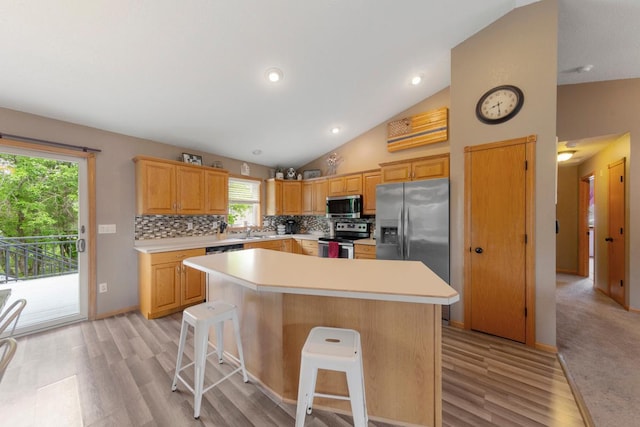 kitchen with stainless steel appliances, light countertops, light wood-type flooring, backsplash, and high vaulted ceiling