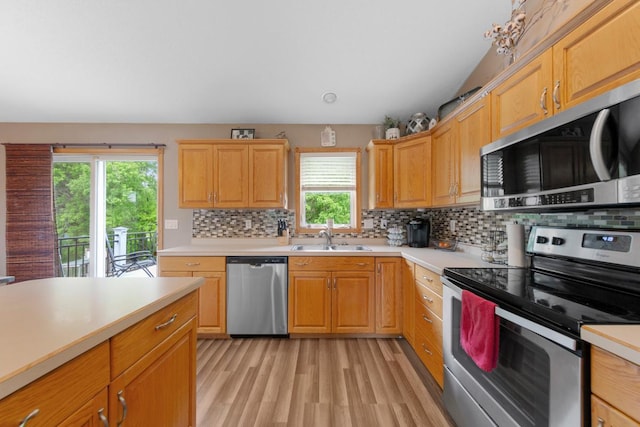 kitchen featuring stainless steel appliances, a sink, light countertops, and decorative backsplash