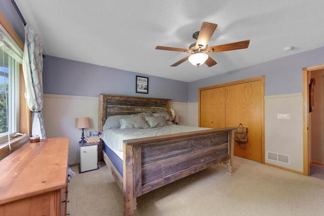 bedroom with light carpet, a ceiling fan, and a closet
