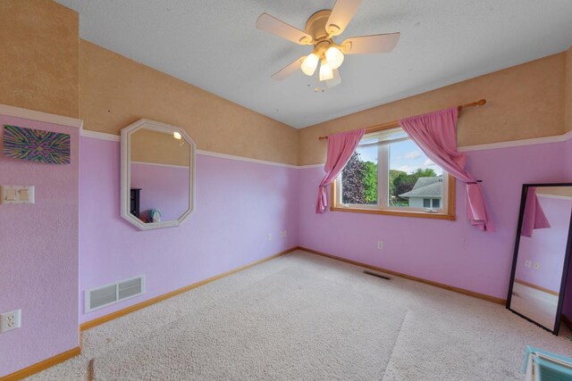 unfurnished room with carpet floors, a ceiling fan, and baseboards