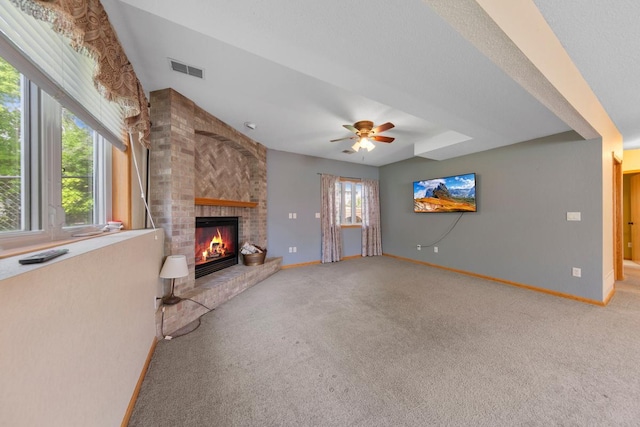 unfurnished living room featuring light colored carpet, a brick fireplace, baseboards, and ceiling fan