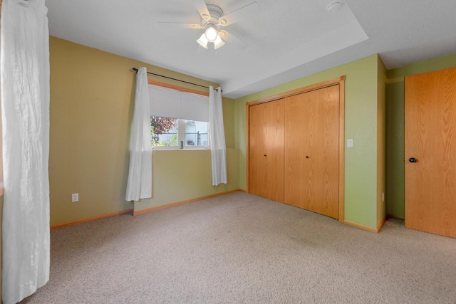 unfurnished bedroom featuring carpet, a closet, baseboards, and ceiling fan