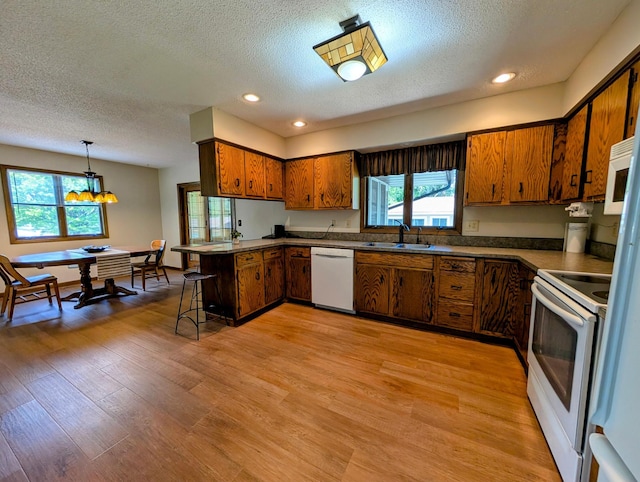 1401 5th St, Montevideo, MN 56265 - kitchen featuring white appliances, a sink, a peninsula, brown cabinets, and a textured ceiling