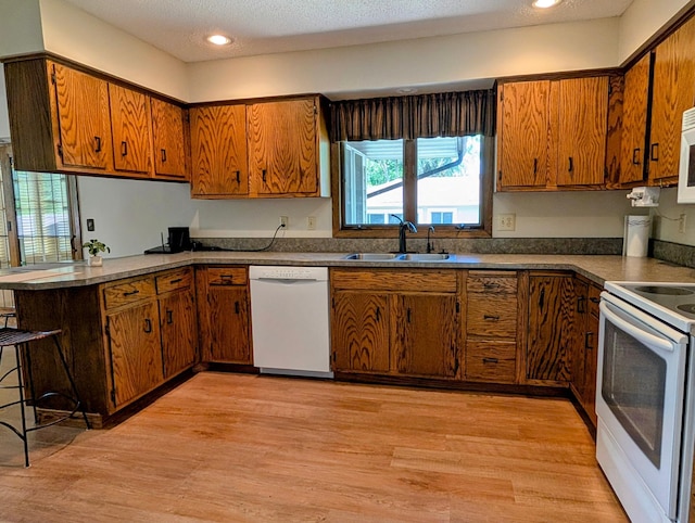 1401 5th St, Montevideo, MN 56265 - kitchen featuring white appliances, brown cabinetry, a sink, a peninsula, and recessed lighting