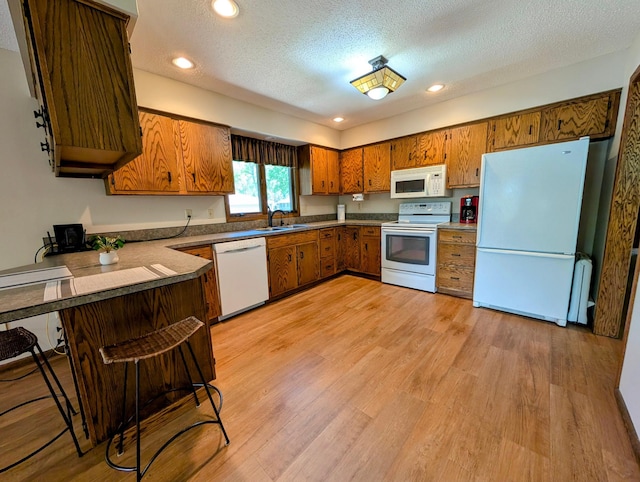 1401 5th St, Montevideo, MN 56265 - kitchen featuring white appliances, a sink, brown cabinetry, a textured ceiling, and a peninsula