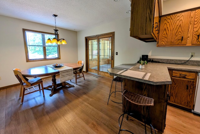 1401 5th St, Montevideo, MN 56265 - dining space with wood finished floors, a chandelier, a textured ceiling, and baseboards
