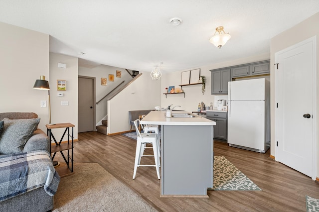 kitchen featuring freestanding refrigerator, gray cabinetry, open floor plan, dark wood-type flooring, and a sink