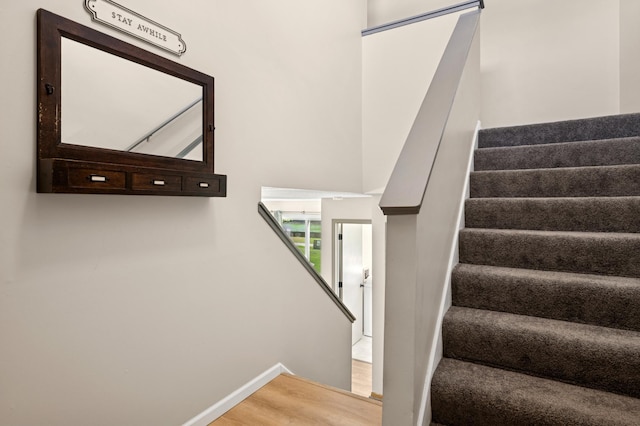 staircase featuring wood finished floors and baseboards