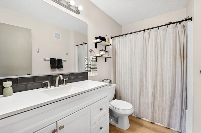 bathroom with wood finished floors, toilet, vanity, a shower with shower curtain, and a textured ceiling