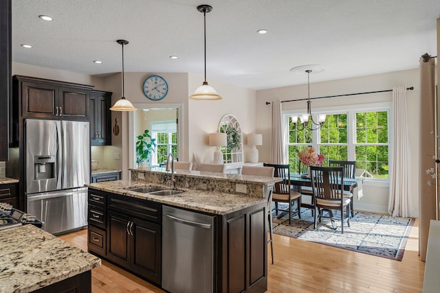 855 Elins Lake Rd SE, Cambridge, MN 55008 - kitchen with stainless steel appliances, a sink, light wood finished floors, hanging light fixtures, and a center island with sink