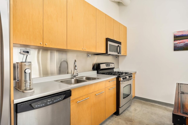 kitchen featuring appliances with stainless steel finishes, a sink, light countertops, baseboards, and concrete flooring