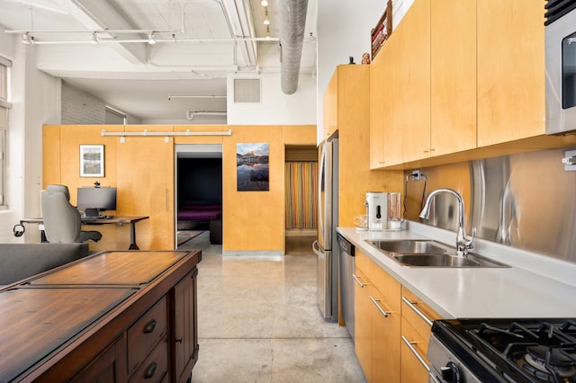 kitchen featuring a sink, appliances with stainless steel finishes, open floor plan, a desk, and light countertops