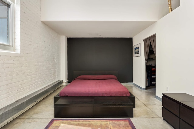 bedroom featuring finished concrete flooring and brick wall