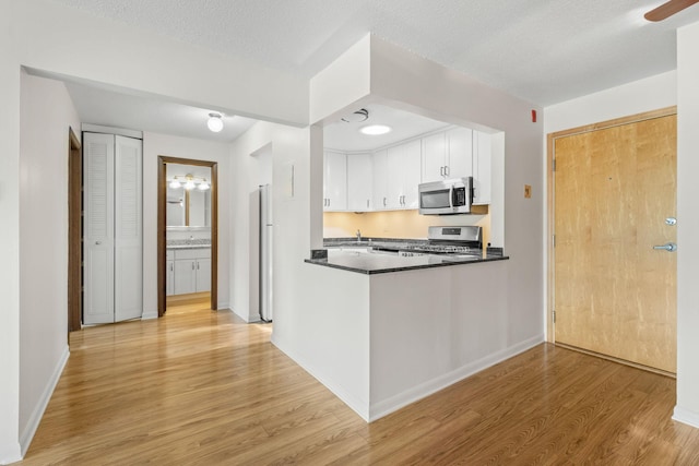 4820 Park Commons Dr Unit 329, Saint Louis Park, MN 55416 - kitchen featuring appliances with stainless steel finishes, light wood finished floors, white cabinetry, dark countertops, and a ceiling fan
