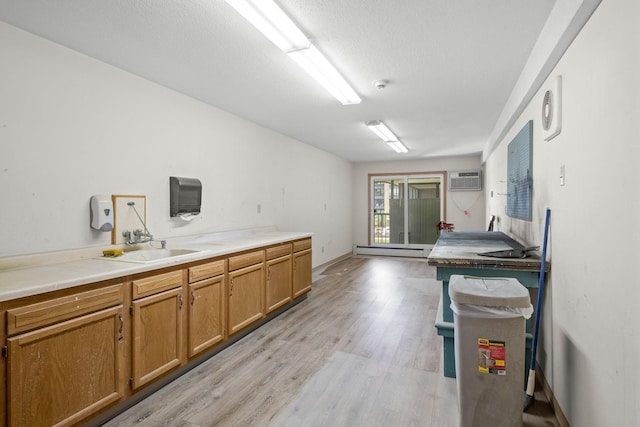 4820 Park Commons Dr Unit 329, Saint Louis Park, MN 55416 - kitchen featuring a baseboard radiator, light wood finished floors, brown cabinetry, a wall mounted air conditioner, and light countertops