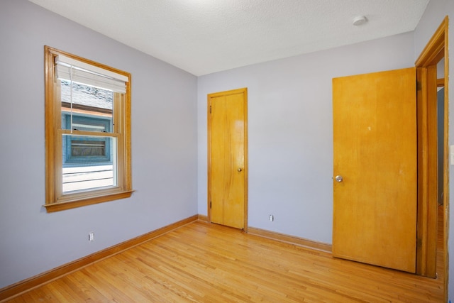4528 6th St NE, Columbia Heights, MN 55421 - unfurnished bedroom with light wood-style flooring, baseboards, and a textured ceiling