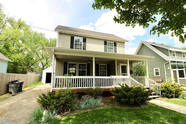 view of front facade featuring a porch, fence, a ceiling fan, a detached garage, and an outdoor structure