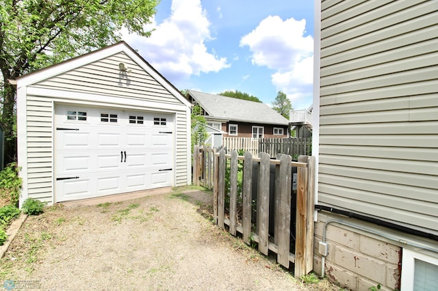 detached garage featuring driveway and fence