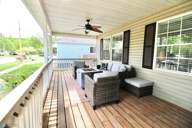 wooden terrace featuring a ceiling fan and an outdoor living space with a fire pit