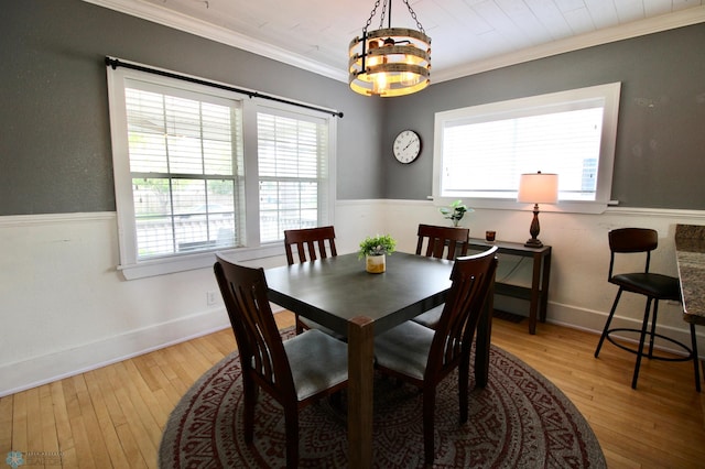 dining space featuring hardwood / wood-style flooring, ornamental molding, a chandelier, and baseboards