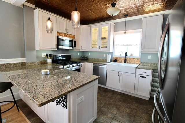 kitchen with appliances with stainless steel finishes, a sink, a peninsula, an ornate ceiling, and white cabinets