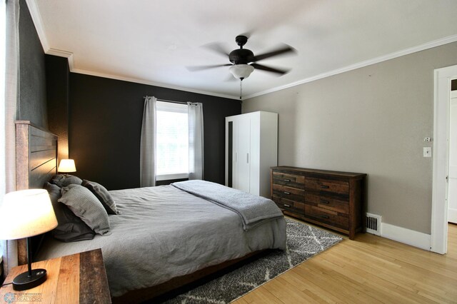 bedroom with wood finished floors, crown molding, baseboards, and a ceiling fan