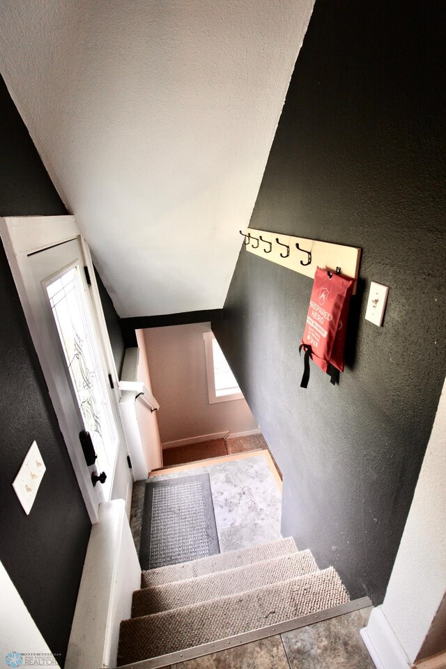 stairs featuring a textured wall and baseboards